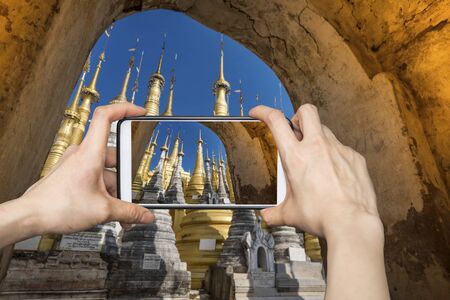 Girl taking pictures on mobile smart phone in Indein village Pagoda, Inle Lake, Myanmarの写真素材