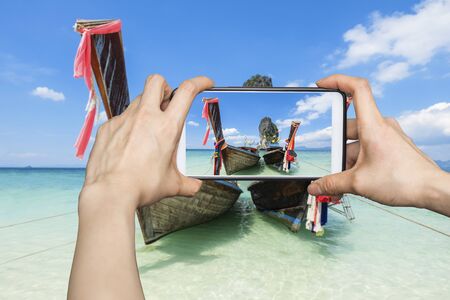 Girl taking pictures on mobile smart phone in poda island karbi,Thailandの写真素材