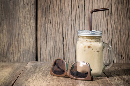 Iced coffee with milk in vintage jar on wood backgroundの写真素材