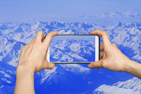 Taking pictures on mobile smart phone in High mountains covered with snowの写真素材