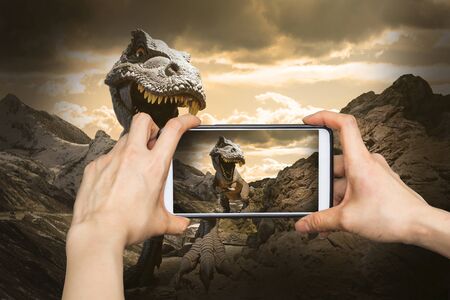 Taking pictures on mobile smart phone in Dinosaurs model on rock mountainの写真素材