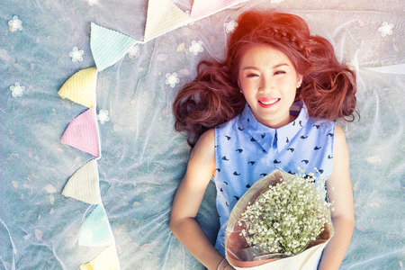 Daisy flowers field holds a young asian womanの写真素材