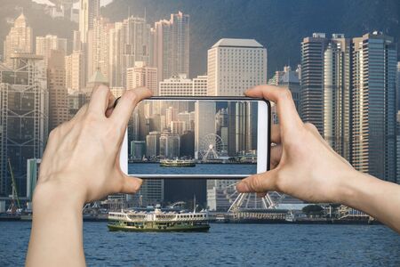 Girl taking pictures on mobile smart phone in Hong Kong's Victoria Harbour in sunriseの写真素材
