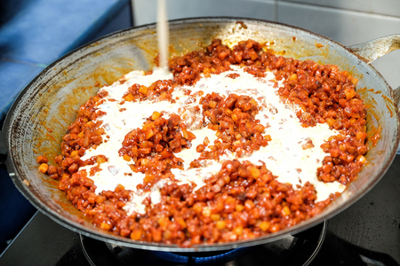 Cooking pork with red sauce and milk in home kitchenの写真素材