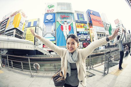 Osaka,Japan - Mar 26, 2013 : A young tourist woman tried to take the same pose as the Glico man neon signboard which is one of the most famous landmark Dontonbori in Namba Osaka,Japan.のeditorial素材