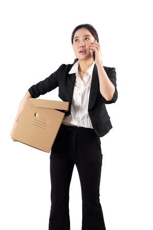 A young woman carrying a box and talking on the phoneの写真素材