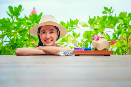 Happy woman with fresh coconut water on the beachの写真素材