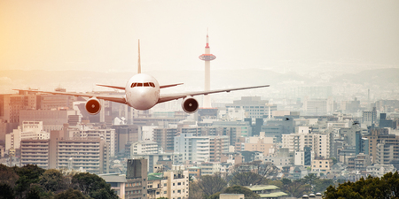 Airplane frying over the kyoto tower backgroundの写真素材