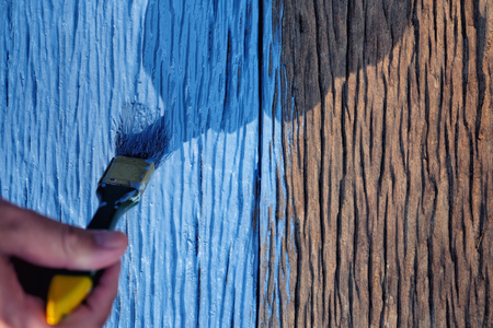 Paintbrush in hand and painting a wooden tableの写真素材