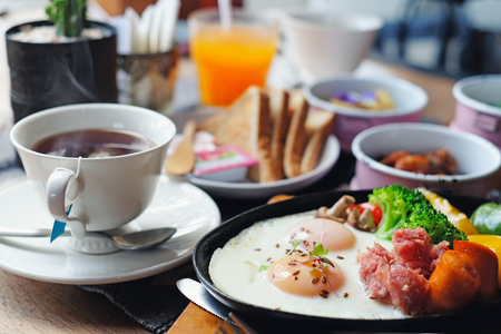 Morning Breakfast - Fried eggs with sausages, fermented pork and vegetable served with toasts, coffee, orange juice and fruitsの写真素材