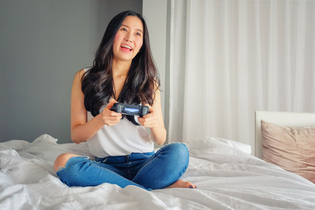 Beautiful girl playing video game on bedの写真素材