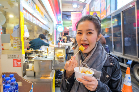 Chinese Asian young female model eating Chinese Steamed Dumpling on Street in Hong Kongの写真素材