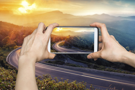 Woman Taking pictures on mobile smart phone showing Beautiful winter sunrise landscape viewpoint at km.41 of Doi Inthanon Chiang Mai Thailandの写真素材