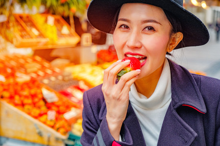 Beautiful Woman eating fresh strawberry on the street market in Germanyの写真素材