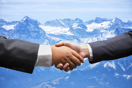 businessmen shaking hands on Snow mountain in Switzerland backgroundの写真素材