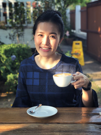 Young woman drinking coffee in in sunshine light enjoying her morning coffee.の写真素材