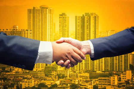Business men shaking hands on cityscape business backgroundの写真素材