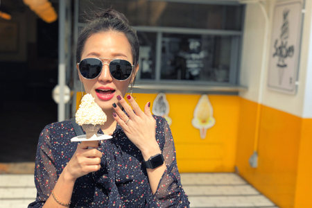 Outdoor closeup fashion portrait of young woman with sunglasses eating ice cream in summer hot weather in Seoul, Koreaの写真素材