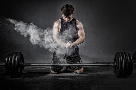 Strong fitness man doing arm workout with barbells in the gymの写真素材