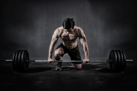 Strong fitness man doing arm workout with barbells in the gymの写真素材