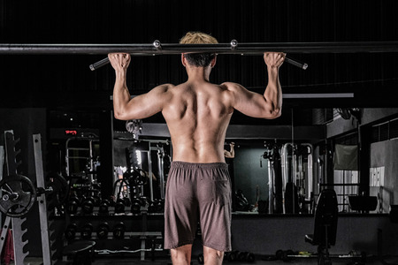 Strong fitness man doing arm workout in the gymの写真素材