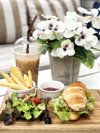 Smoked salmon croissant sandwich served with coffee and french friedの写真素材