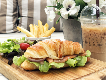 Smoked salmon croissant sandwich served with coffee and french friedの写真素材