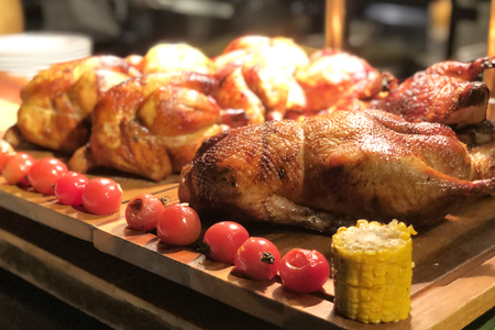 Roasted chicken with tomato and corn on wooden tableの写真素材