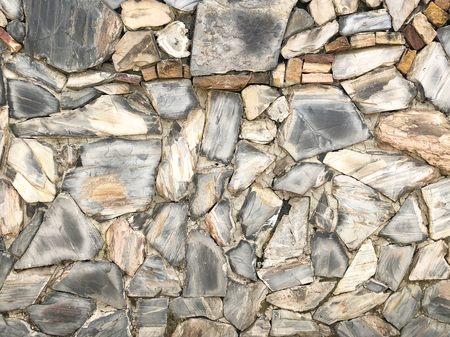 Rock wall pattern gray color of modern style design decorative uneven cracked real stone wall surface with cementの写真素材