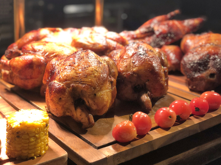 Roasted chicken with tomato and corn on wooden tableの写真素材