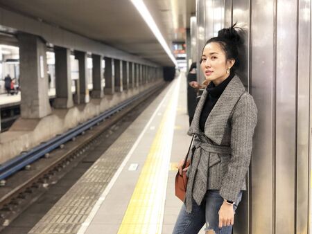 Beautiful young woman with smiling waiting a train at subway stationの写真素材
