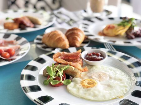 Delicious breakfast served with coffee, orange juice, egg, ham, bacon rolls at the luxury hotelの写真素材