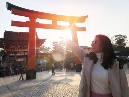 Young woman tourist travel Kyoto, Japan at Fushimi Inari Shrine main gate at sunriseの写真素材