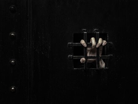 Horror woman locked in dark cage hand holding cage scary scene halloween conceptの写真素材