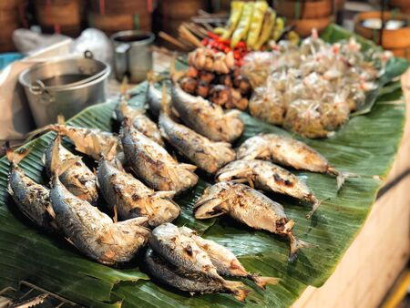 Fried mackerels on banana leaf Thai style bamboo basket for sell in street market.の写真素材