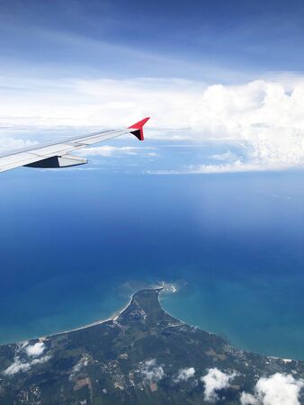 Wing of an airplane flying above the ocean の写真素材
