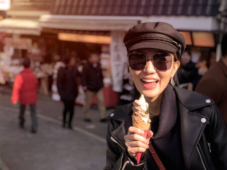 Young tourist woman eating ice cream cone covered with real gold leaf a famous street food in Japanの写真素材