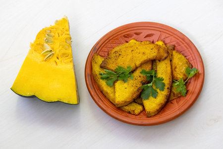 Thinly sliced fried sweet pumpkin fry on a clay plate, with a small piece of pumpkin cut beside it.の写真素材