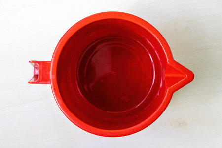 Top view of a red plastic mug on a light wooden surface.の写真素材