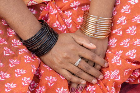 Close-up of a beautiful Bengali woman's hands adorned with colorful glass bangles, a ring, and nail...
