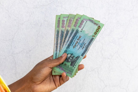 A female hand holding Bangladeshi money 500 taka notes in white background.の写真素材