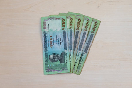 500 Taka Bangladeshi currency notes displayed on a wooden background.