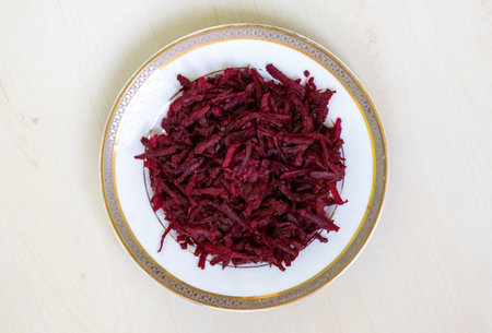 Thinly sliced or grated beetroot fritters are presented on a white ceramic plate against a light...