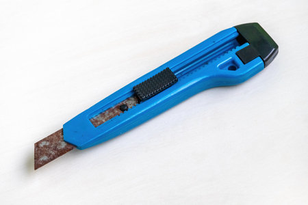 An old, rusty, blue cutter knife on a white background.