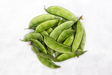 Fresh green hyacinth beans against a white background. Top view.