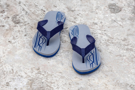 A pair of stylish flip-flops on a concrete floor. Flip-flops are a type of light, sandal-like shoe, typically worn as casual footwear.の写真素材