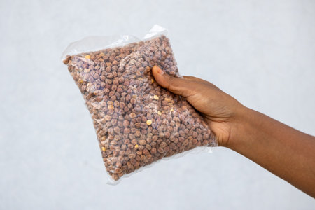 Female hand showing a clear plastic package of raw chickpeas, just bought at the market. Excellent...