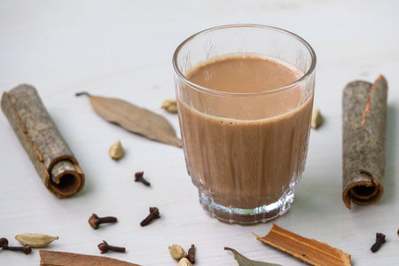 Delicious masala tea in a clear glass, featuring aromatic spices like cinnamon, cardamom, cloves,...