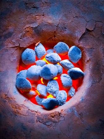 Close-up of burnt charcoal, coals burning in clay stove.