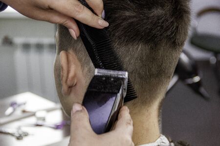 hairdresser at the hairdresser's salon makes a modern haircut and hairstyle teenagerの写真素材